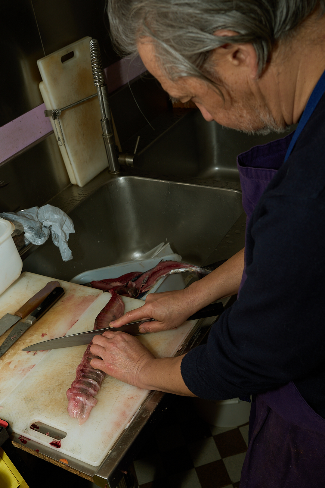 Christian Qi taille un filet de poisson près de l'évier